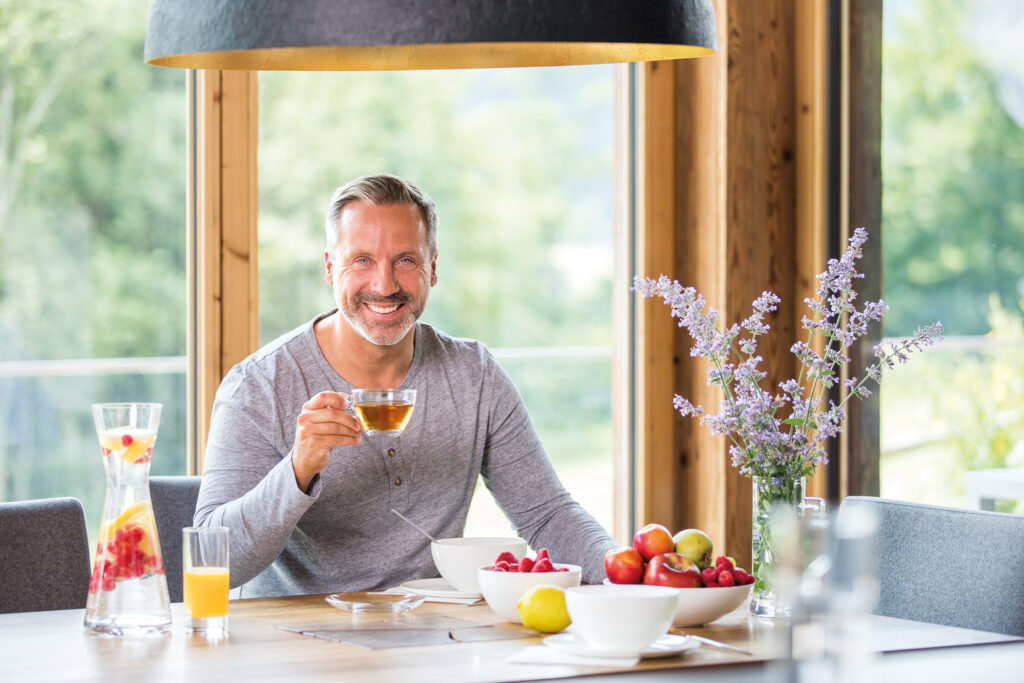 Mann beim Frühstück mit Tasse Tee in der Hand